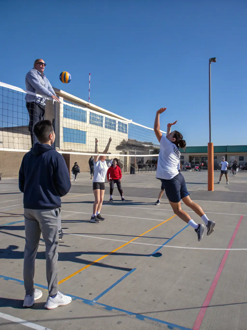 A group of adults participating in a volleyball match on an outdoor court, emphasizing the social and active nature of the program.
